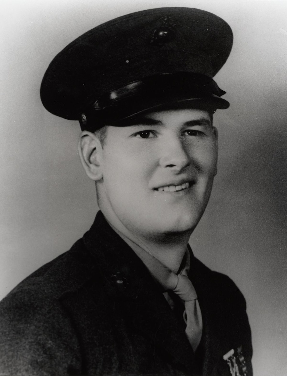 A man in a World War II uniform and cap smiles.