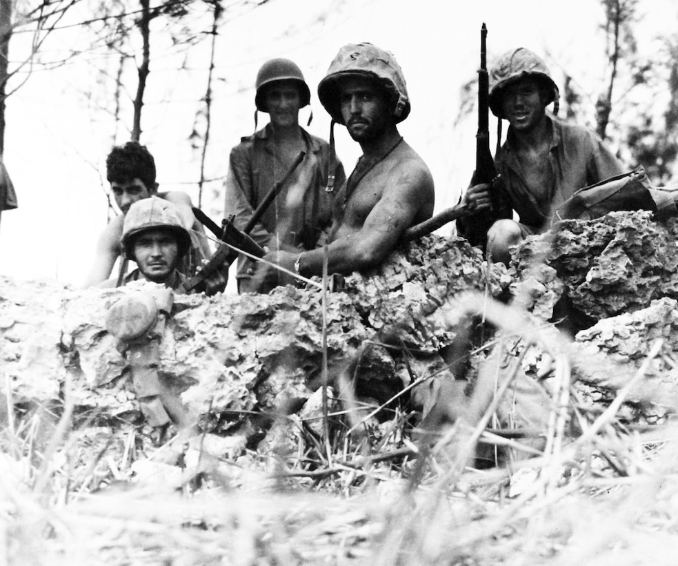 Five Marines in helmets stand in a hole.