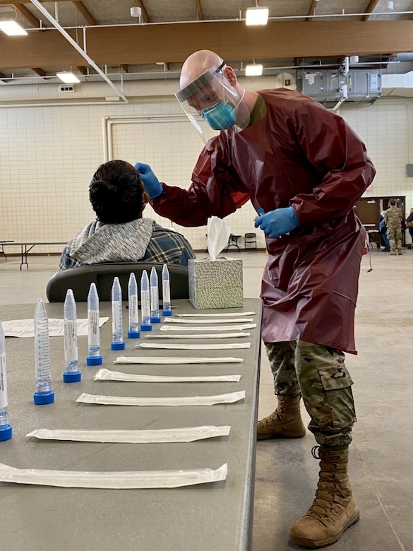 A medical technician in personal protective equipment performs a COVID-19 test.