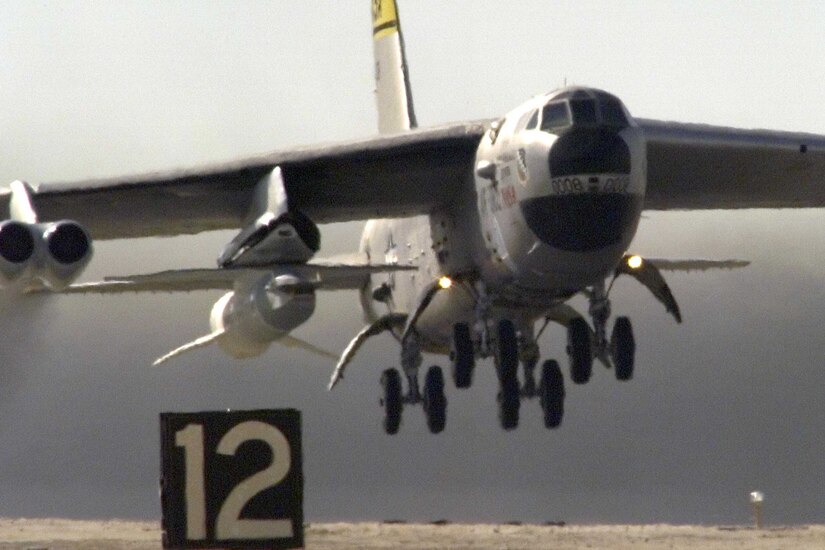 B-52 lifts off carrying a small rocket under its wing.