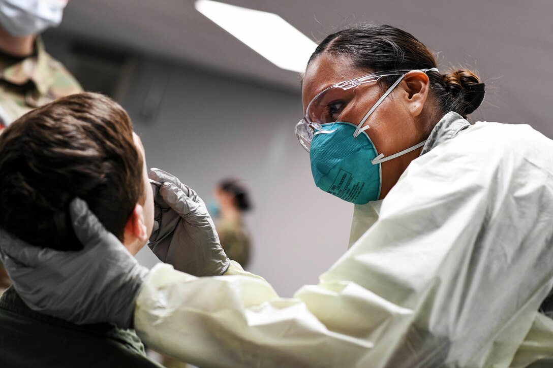 An airman wearing personal protective equipment tests a patient for COVID-19.