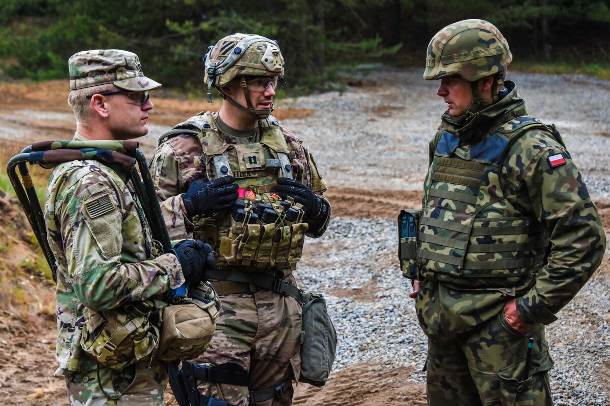 U.S., Polish soldiers speak in the field.