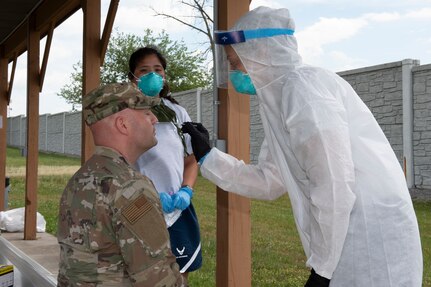 Col. Bill Annie, 167th Mission Support Group commander receives a COVID-19 test swab from 167th Medical Group medical technician Tech. Sgt. Kristin Ganley, as Tech. Sgt. Taryn Burkhart also a medical technician, waits to collect the sample at the 167th Airlift Wing, Martinsburg, W. Va., June 11, 2020. Airmen returned to base for the first unit training assembly in two months, after regularly-scheduled training events were cancelled in April and May because of COVID-19 precautions.