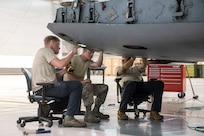 Tech Sgt. Daniel Barrow, Staff Sgt. Doug Miller and Staff Sgt. Kevin Cecil sit in office chairs, just the right height to comfortably repair damage to the cargo ramp on a C-17 Globemaster III aircraft at the 167th Airlift Wing, Martinsburg, W.Va., May 28, 2020.