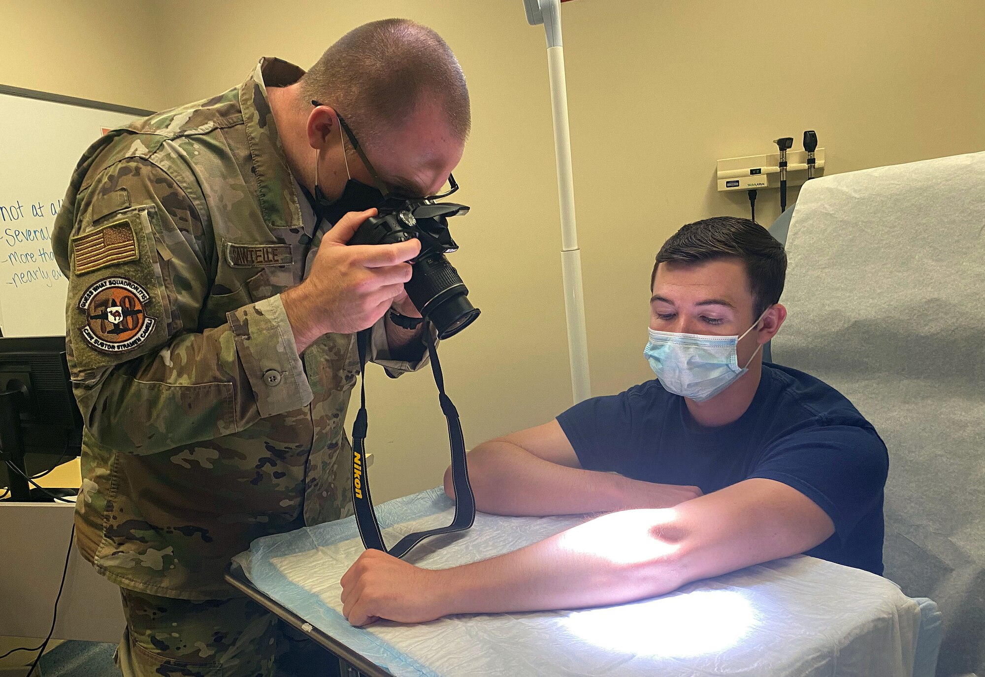 Photo shows a picture of an Airman taking the picture of a patient's arm.