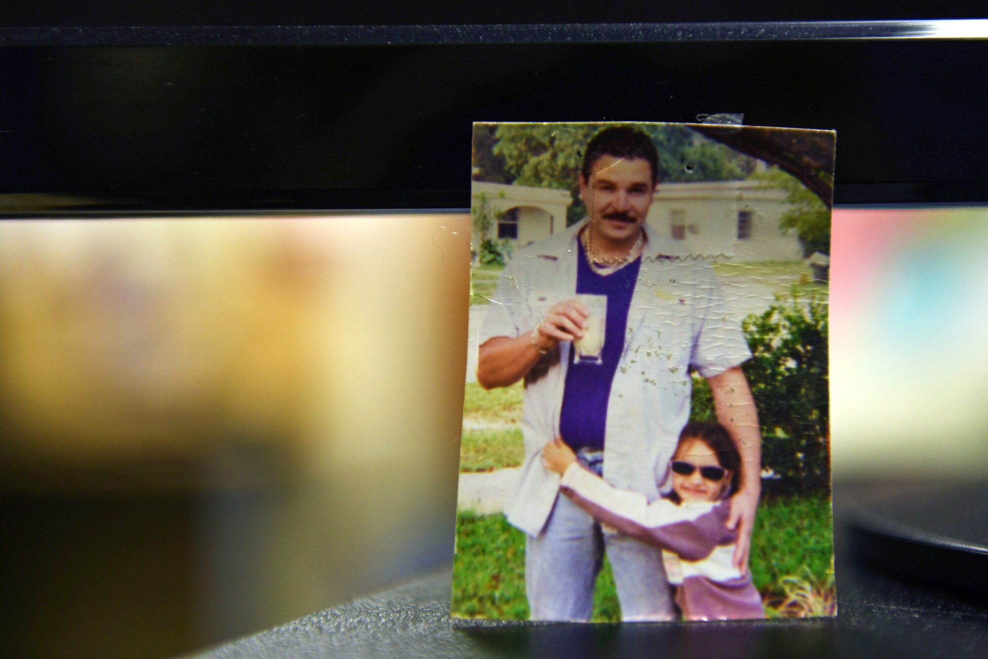 A photo of U.S. Air Force Airman 1st Class Ericka. A. Woolever as a child and her father Ivan Martinez sits on a desk, June 19, 2020 at Aviano Air Base, Italy. Martinez made a difference and a genuine impact in Woolever’s life. (U.S. Air Force photo by Airman 1st Class Ericka. A Woolever)