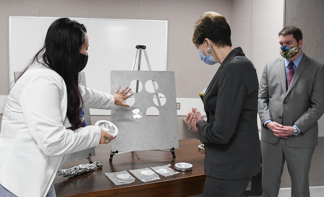 Kellye Burns, left, a space test engineer, shows Secretary of the Air Force Barbara Barrett some of the hardware and samples used during a materials test in teh Space Threat Assessment Testbed at Arnold Air Force Base, Tenn., June 18, 2020. Also pictured is John Claybrook, capability manager for Space Asset Resilience. (U.S. Air Force photo by Jill Pickett)