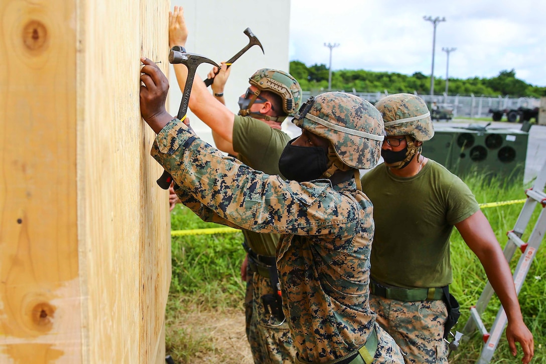 Marines hammer nails into a wall.