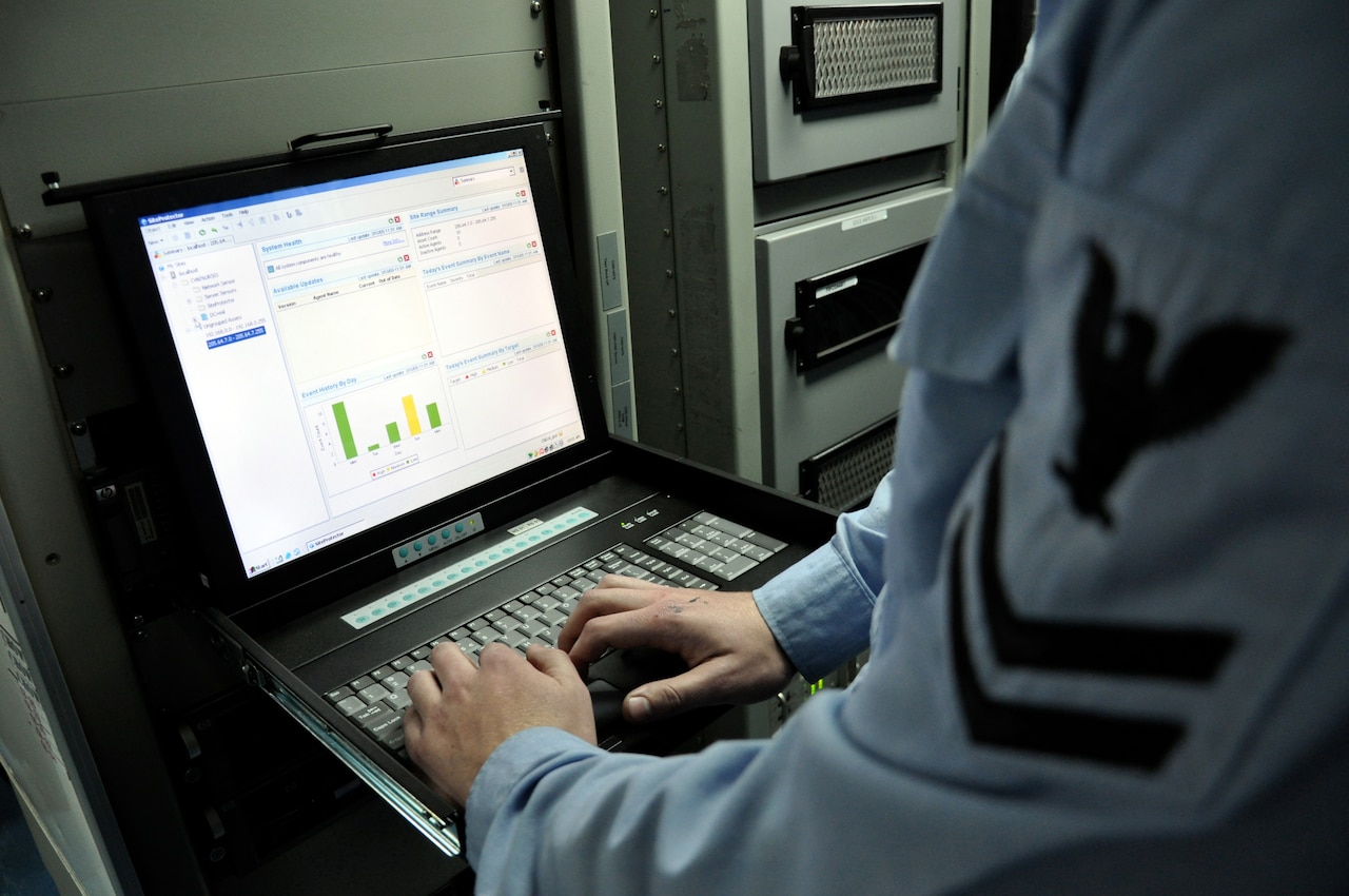 A service member works on a computer.