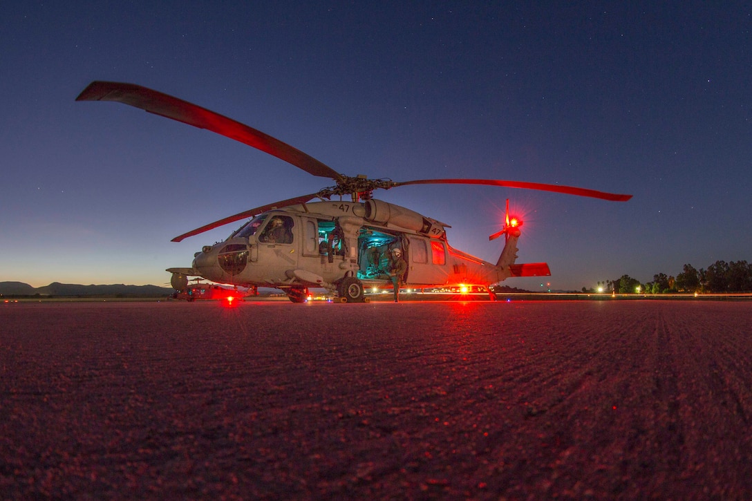 A Navy helicopter sits parked at night.