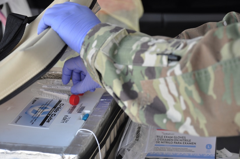 Closeup of hands wearing purple latex gloves processing medical samples.