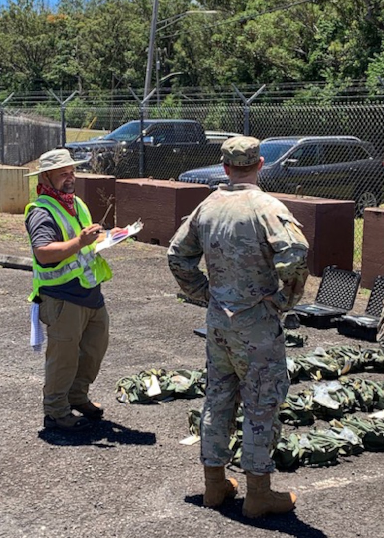 A civilian worker and an Army soldier stand and talk outside.