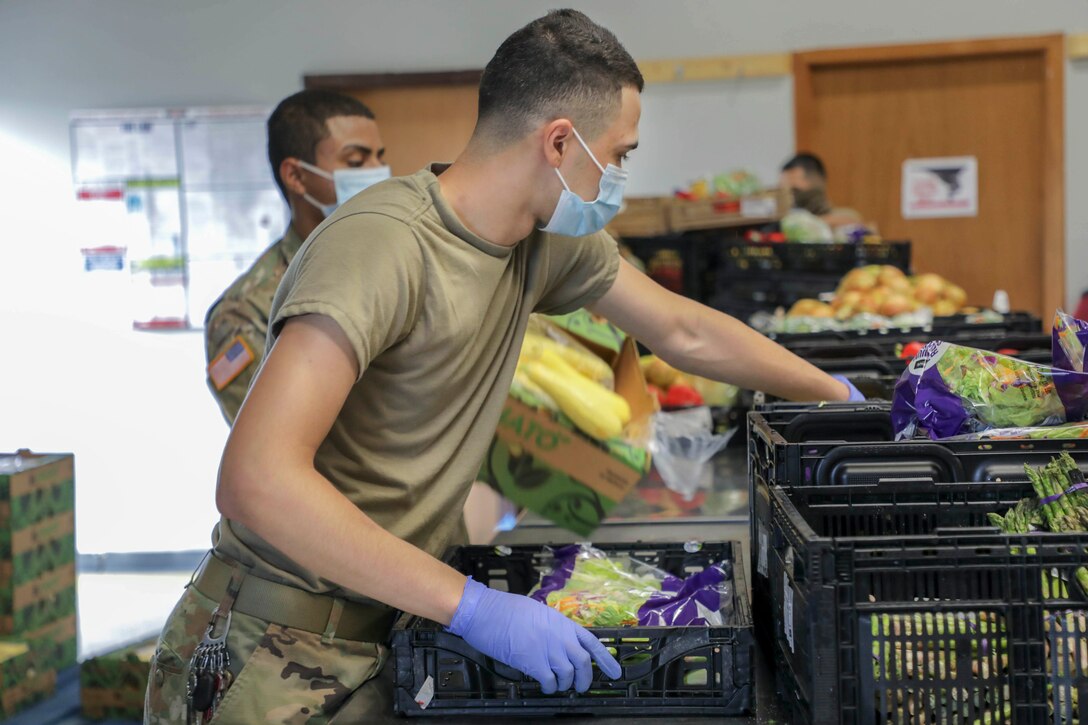 A soldier packs food into a crate.