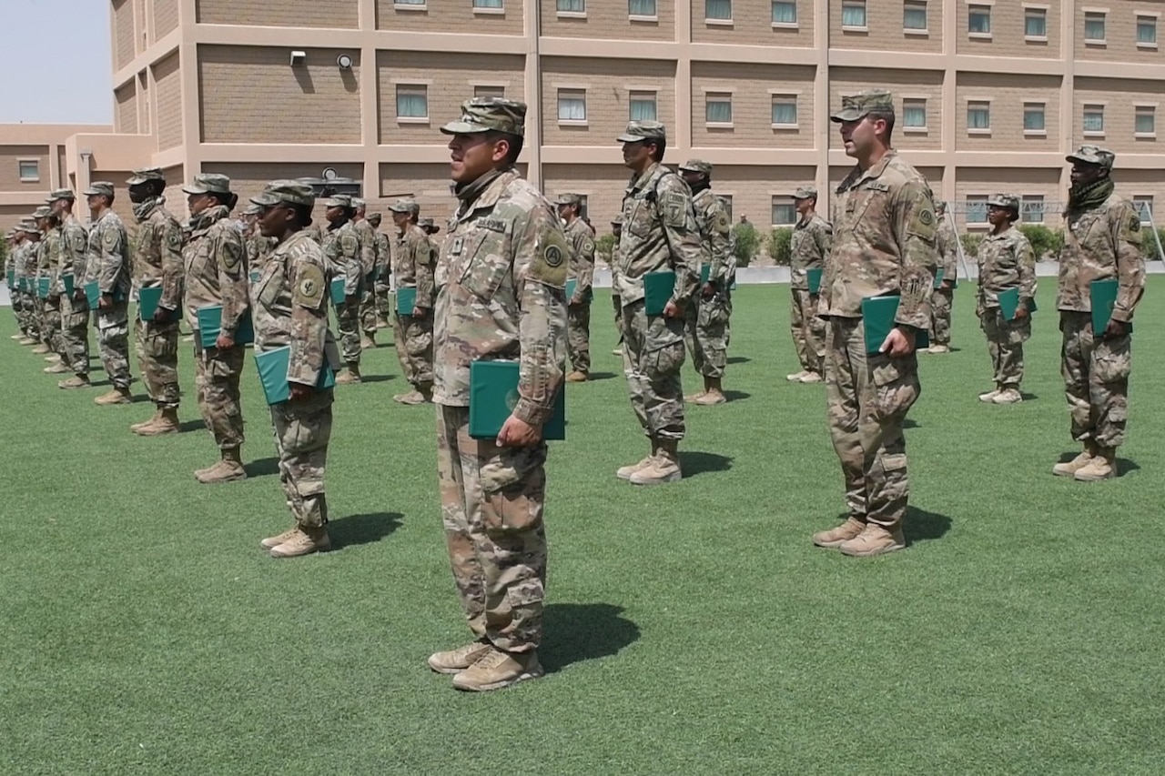 Soldiers stand socially distanced in a formation.