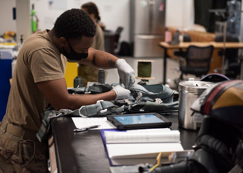Senior Airman Melvin Wells, 57th Weapons Support Squadron aircrew flight equipment technician, inspects a harness at Nellis Air Force Base, Nev., June 3, 2020. AFE technicians assigned to the WPSS repair flight and aircrew equipment for 18 different aircraft used by the school. (U.S. Air Force photo by Airman 1st Class Bryan Guthrie)