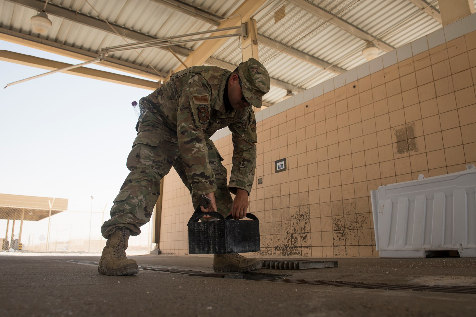 U.S. Air Force Senior Airman Fernando Jimenez, a vehicle operator assigned to the 379th Expeditionary Logistics Readiness Squadron, removes a prototype drainage pan from a vehicle wash rack at Al Udeid Air Base, Qatar, June 13, 2020.