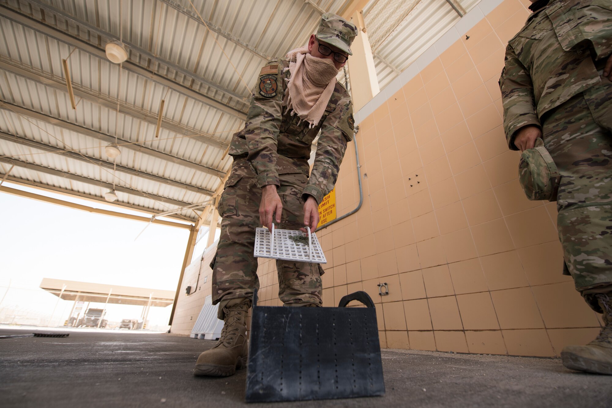 U.S. Air Force Staff Sgt. Justin Grahn, a vehicle operator assigned to the 379th Expeditionary Logistics Readiness Squadron, inspects a prototype drainage pan from a vehicle wash rack at Al Udeid Air Base, Qatar, June 13, 2020.