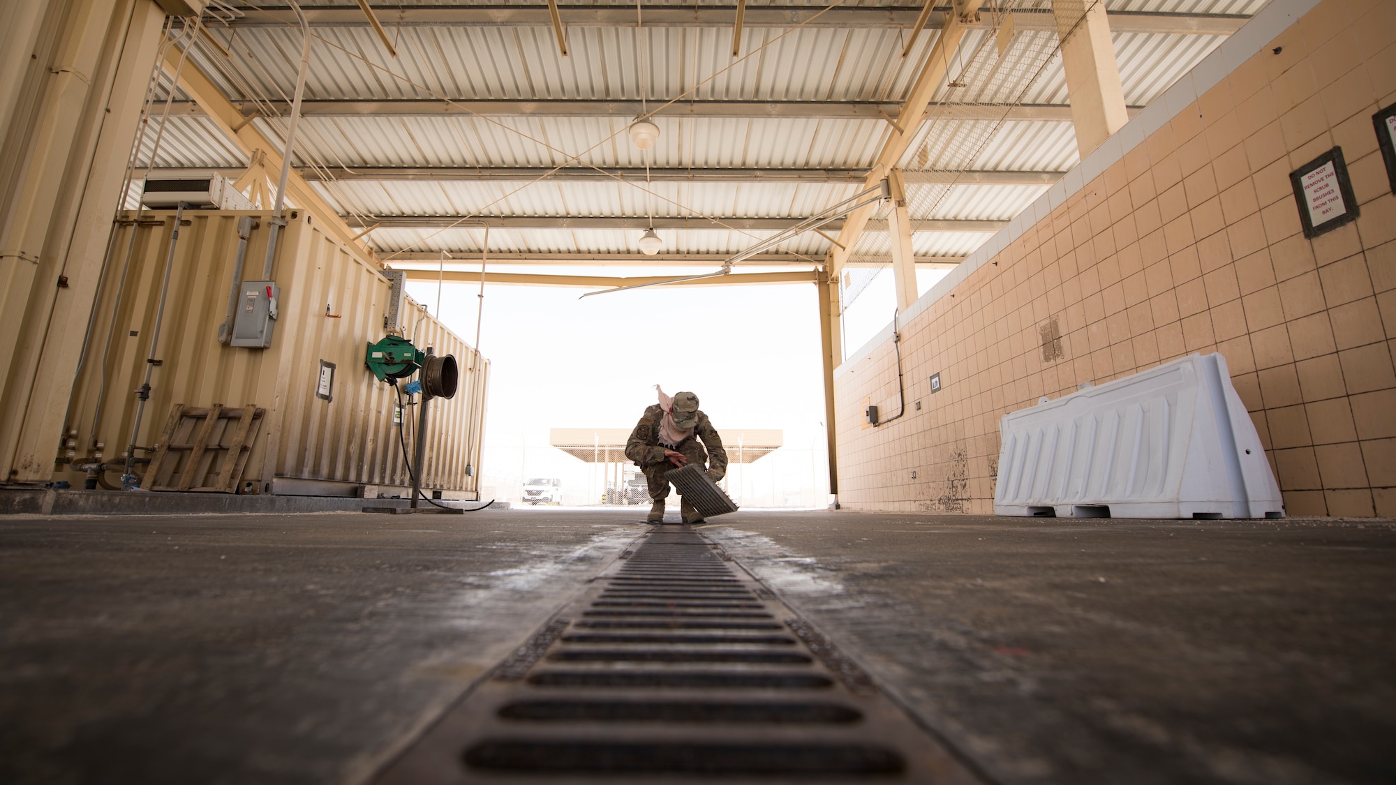 U.S. Air Force Staff Sgt. Justin Grahn, a vehicle operator assigned to the 379th Expeditionary Logistics Readiness Squadron, inspects a prototype drainage pan from a vehicle wash rack at Al Udeid Air Base, Qatar, June 13, 2020.