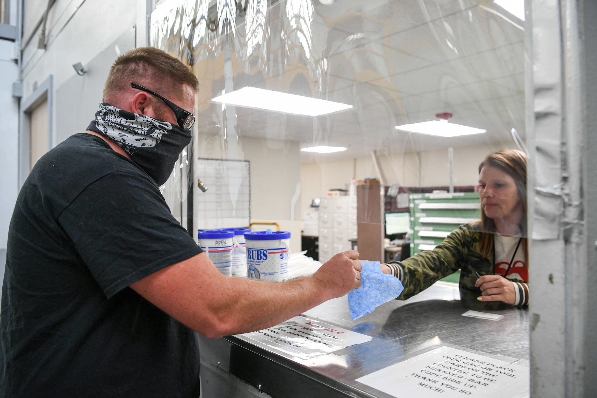 Graham Satterfield, a C-130 maintainer, hands over a tool with a clean wipe to Chelsie Green, a tool attendant in a 309th Maintenance Support Group tool crib.