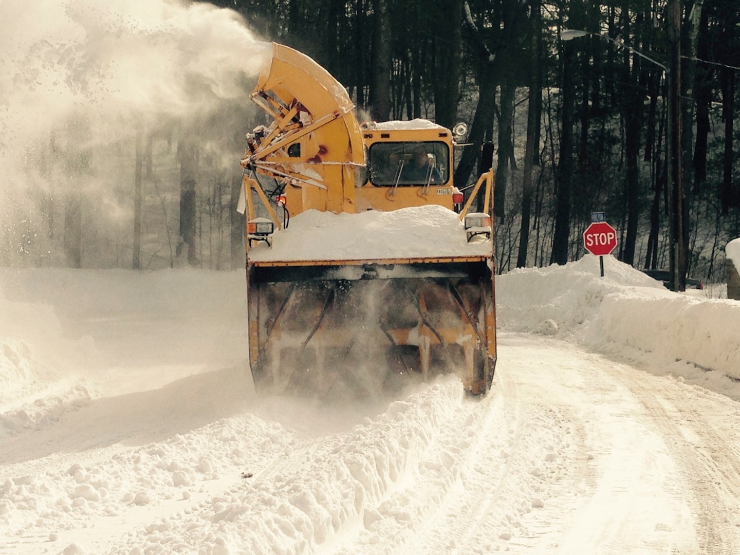 A former military snowblower drives a snowy road.