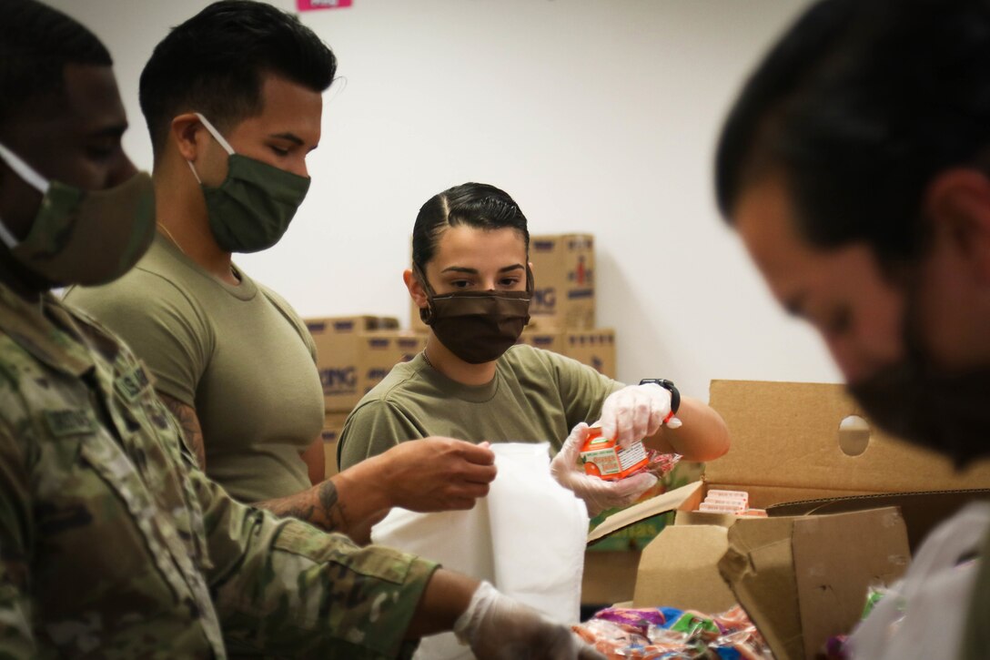 Soldiers wearing face masks assemble packaged meals.
