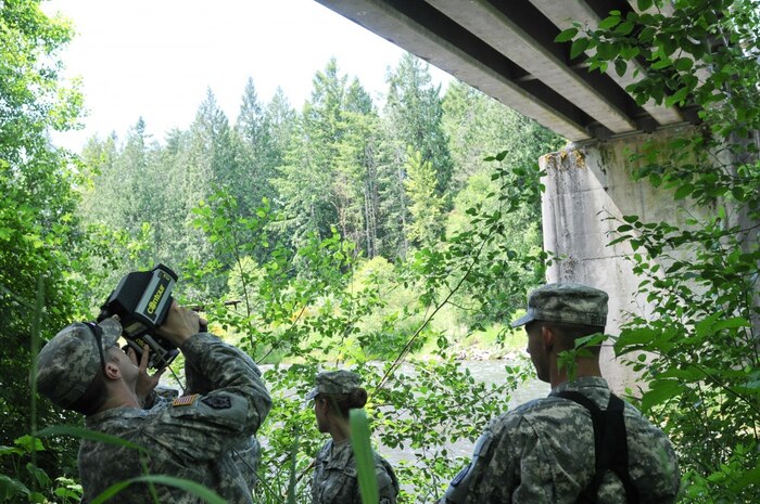 Spc. Christopher Carr (left) and Spc. William Belanger (right) with the 610th Engineer Support Company use a laser range finder to gather and record data on the Nisqually River Bridge while training with the new ENFIRE system June 5. Soldiers with the 14th Eng. Bn., spent a week training on the ENFIRE system which is a digital reconnaissance and surveying equipment instrument set. (US Army photo by Sgt. Austan R. Owen.)