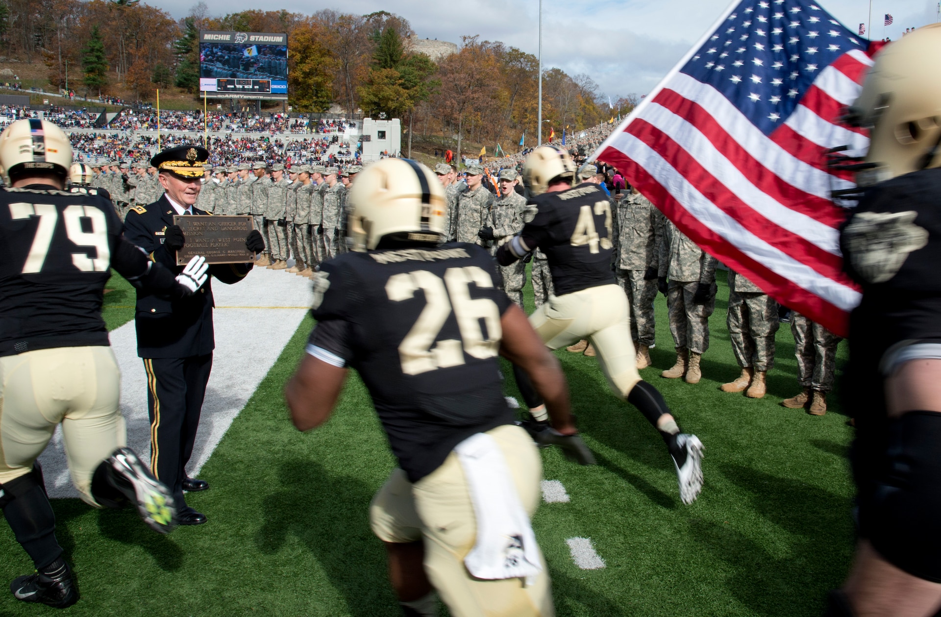 Chairman of the Joint Chiefs of Staff Gen. Martin E. Dempsey holds the Gen. George C. Marshall plaque for Army Black Knight football players to touch as they rush the field to start the Army versus Air Force game in West Point, N.Y., Nov. 3, 2012.