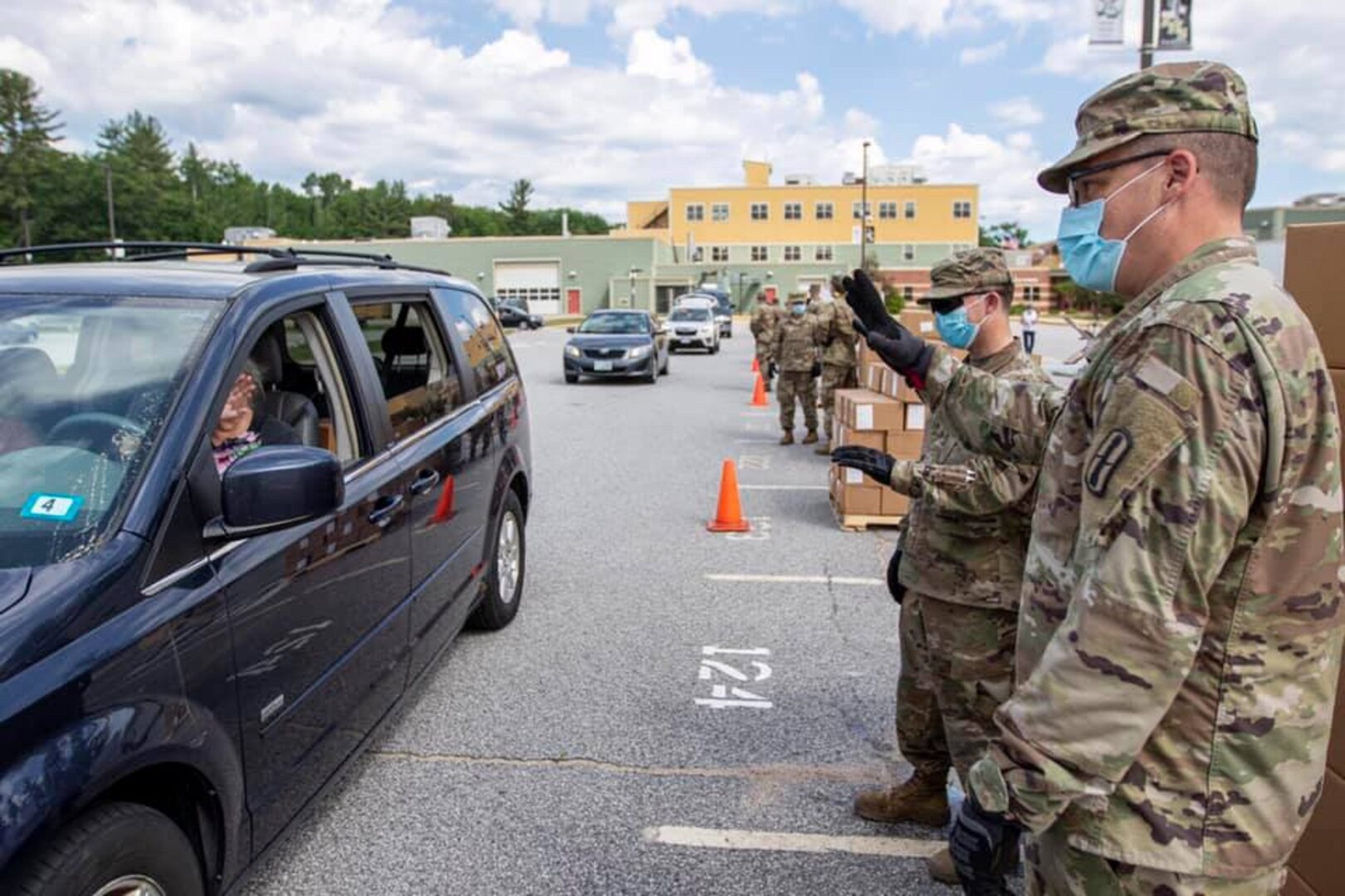 From rear, Pvt. Todd Greeson, an ammunition specialist with 3643rd Brigade Support Battalion, and Pfc. Kevin Blackstone, a radar repair specialist with 197th Field Artillery Brigade, wave to a family after loading their vehicle at a mobile pantry June 12 in North Conway.
