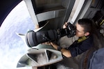 Mass Communication Specialist 1st Class John  Grandin uses a Nikon camera to take photos of an approaching ship on the fantail of Nimitz-class aircraft carrier USS Carl Vinson (CVN 70).