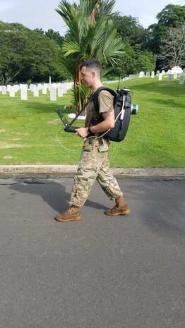 Spc. Zachary Wright, an Engineer Soldier with the 512th Engineer Detachment walks along a road in Corozal American Cemetery in Panama City, Panama, June 28, 2018, with a Light Detection and Ranging (LiDAR) system, which works by sending out a beam of light and measuring the time it takes to return to the sensor. Wright is working as part of a certifying program to ensure precision and accuracy at the final resting places of American service members. The pilot program is supported through a cooperative effort between the American Battle Monuments Commission, Arlington National Cemetery, the United States Army Corps of Engineers, the Army GeoSpatial Center and Product Director Combat Terrain Information Systems. (U.S. Army Photo/Courtesy USACE)