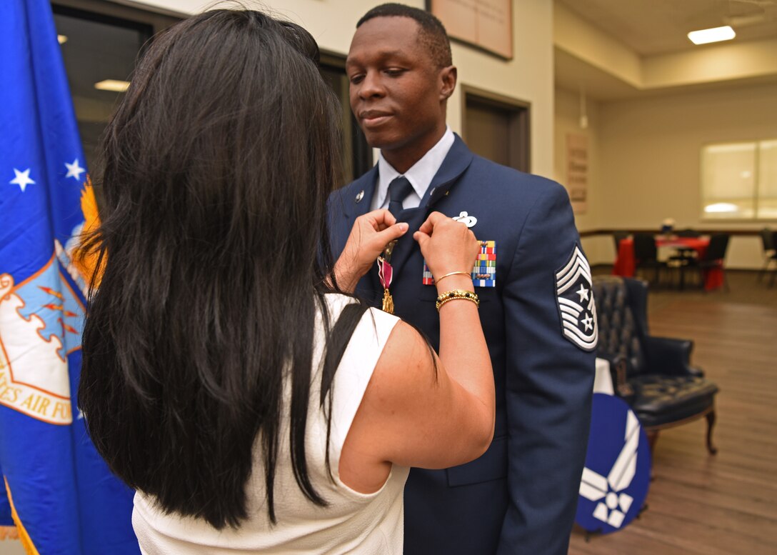 Spouse Michelle Kirkpatrick pins a retirement emblem on the uniform of U.S. Air Force Chief Master Sgt. Lavor Kirkpatrick, during his retirement ceremony at the Cressman dining facility on Goodfellow Air Force Base, Texas, June 19, 2020. Kirkpatrick was the command chief of the 17th Training Wing and retired after serving a total of 23 years to his country. (U.S. Air Force photo by Airman 1st Class Abbey Rieves)