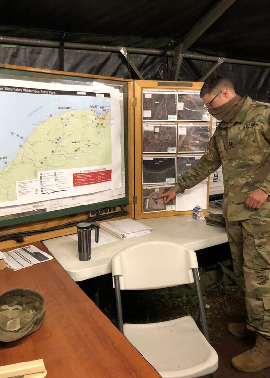 A soldier points to a photograph posted next to a map of part of Michigan’s shoreline.