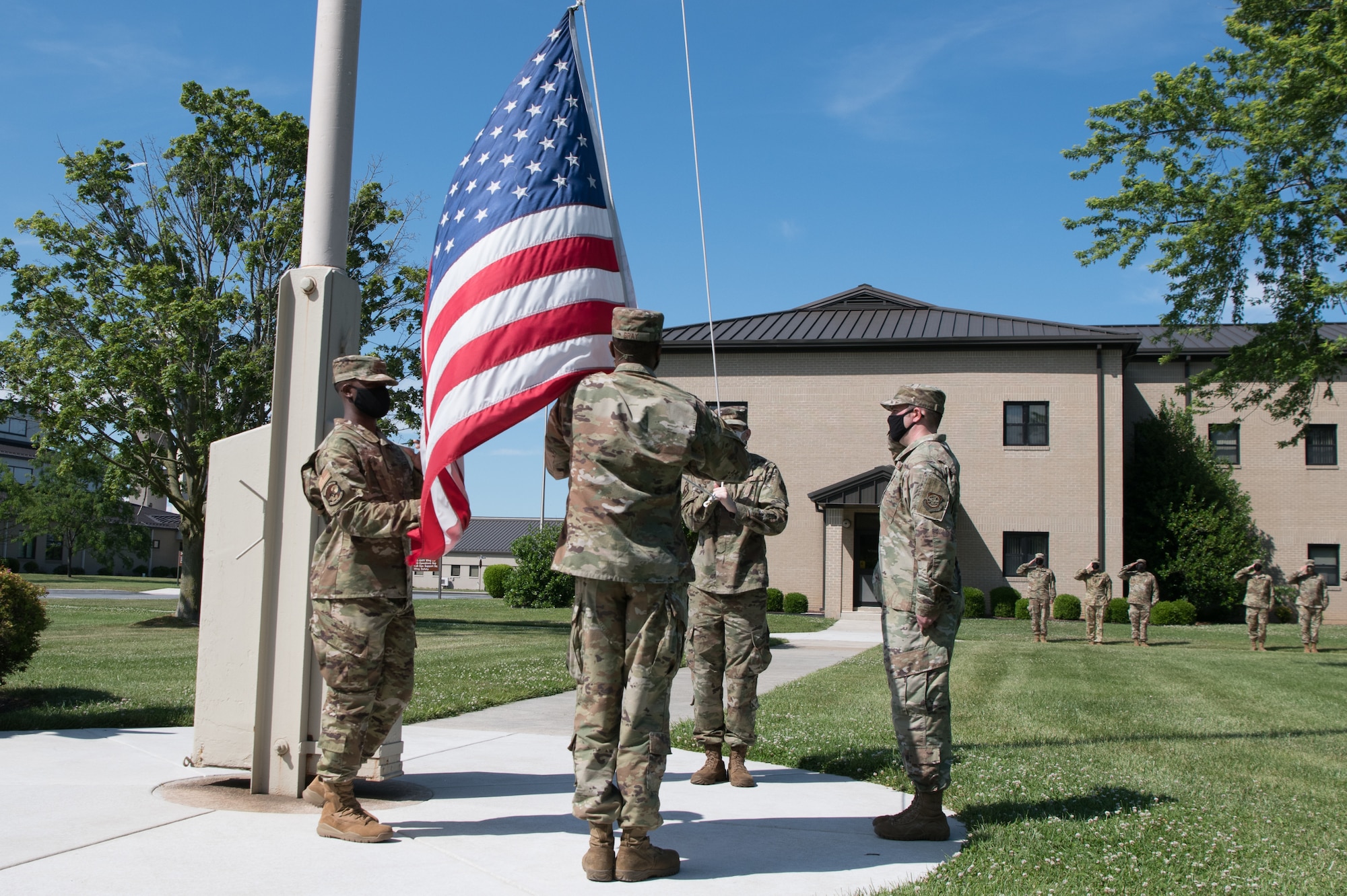 Airmen of the 436th Operations Support Squadron lower the American flag during a retreat ceremony June 18, 2020, at Dover Air Force Base, Delaware. Squadrons throughout Dover AFB take turns performing the ceremony during the summer months. (U.S. Air Force photo by Mauricio Campino)