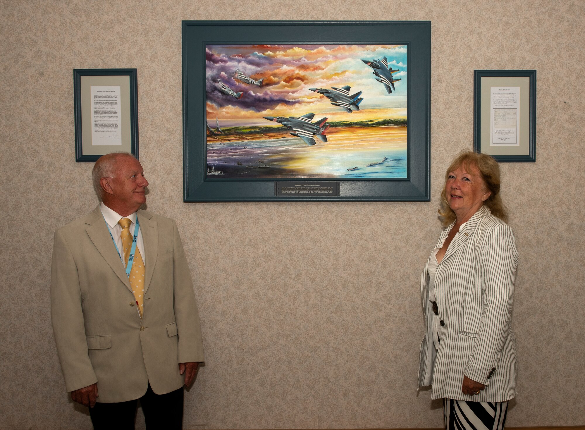 Colin Mason, 48th Mission Support Group Honorary commander, and his wife Elizabeth, stand next to the artwork they created for the 48th Fighter Wing at Royal Air Force Lakenheath, England, June 19, 2020. The painting is a tribute to 48th FW history and it’s involvement in D-Day at Normandy, France during World War II. (U.S. Air Force photo by Airman 1st Class Jessi Monte)