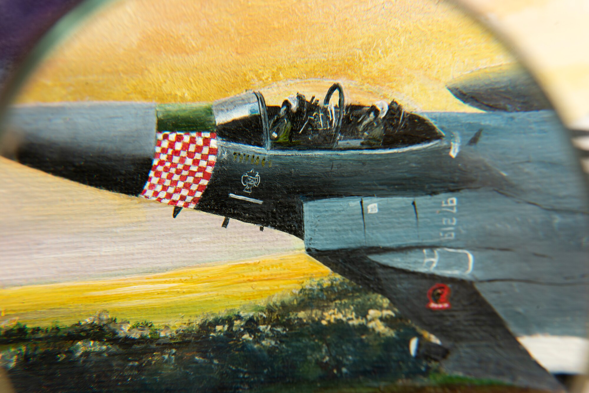 Fine details can be seen through a magnifying glass on a painting presented on behalf of Colin Mason, 48th Mission Support Group Honorary commander, and his wife Elizabeth, to the 48th Fighter Wing at Royal Air Force Lakenheath, England, June 19, 2020. The painting is a tribute to 48th FW history and it’s involvement in D-Day at Normandy, France during World War II. (U.S. Air Force photo by Airman 1st Class Jessi Monte)