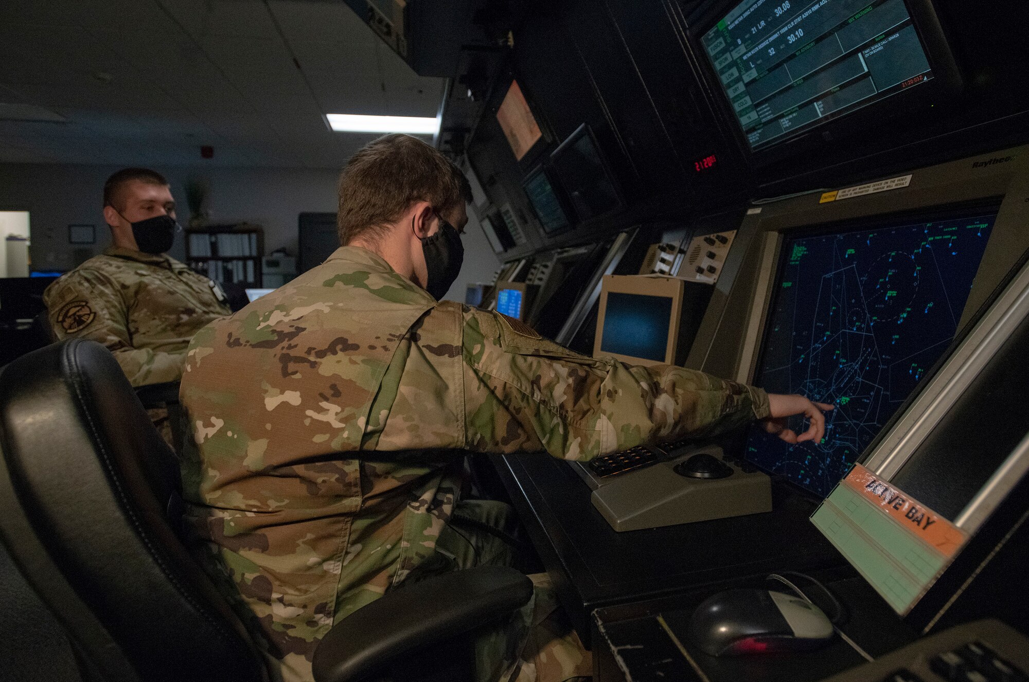U.S. Air Force Senior Airman Nathan Scott, right, and Staff Sgt. Austin Keltner, left, 60th Operation Support Squadron air traffic controllers, monitor aircraft at the Radar Approach Control flight operation center May 5, 2020, at Travis Air Force Base, California. The coronavirus pandemic has affected RAPCON daily operations due to the significant decrease in civilian and military air traffic. To help mitigate the spread of the coronavirus, the RAPCON has reduced the size of the crews on duty in addition to requiring cloth face coverings, and the frequent sanitization of the touch screen equipment. (U.S. Air Force photo by Heide Couch)