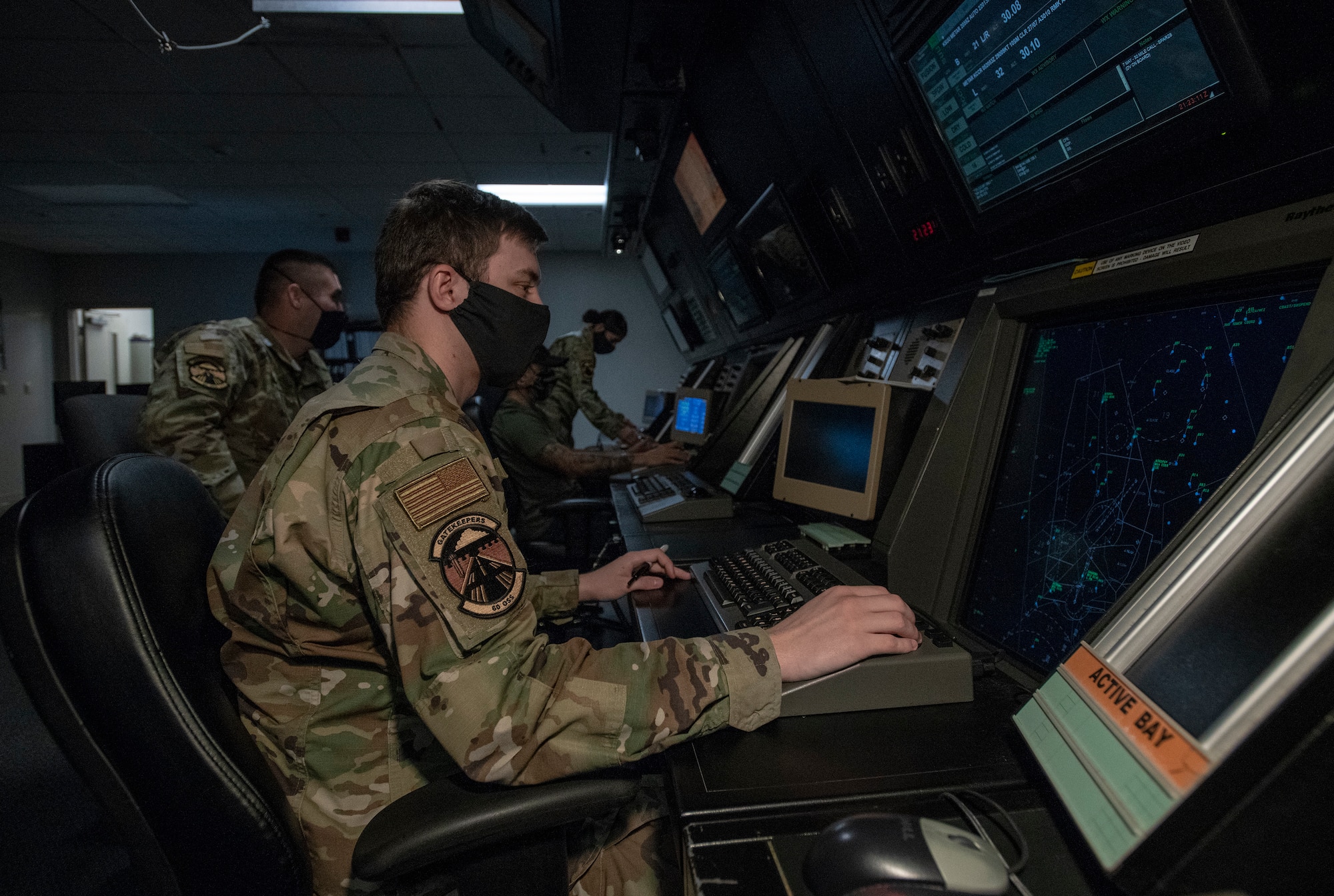 U.S. Air Force air traffic controllers assigned to the 60th Operations Support Squadron Radar Approach Control, monitor the airspace May 5, 2020, at Travis Air Force Base, California. The coronavirus pandemic has affected RAPCON daily operations due to the significant decrease in civilian and military air traffic. To help mitigate the spread of the coronavirus, the RAPCON has reduced the size of the crews on duty in addition to requiring cloth face coverings, and the frequent sanitization of the touch screen equipment. (U.S. Air Force photo by Heide Couch)