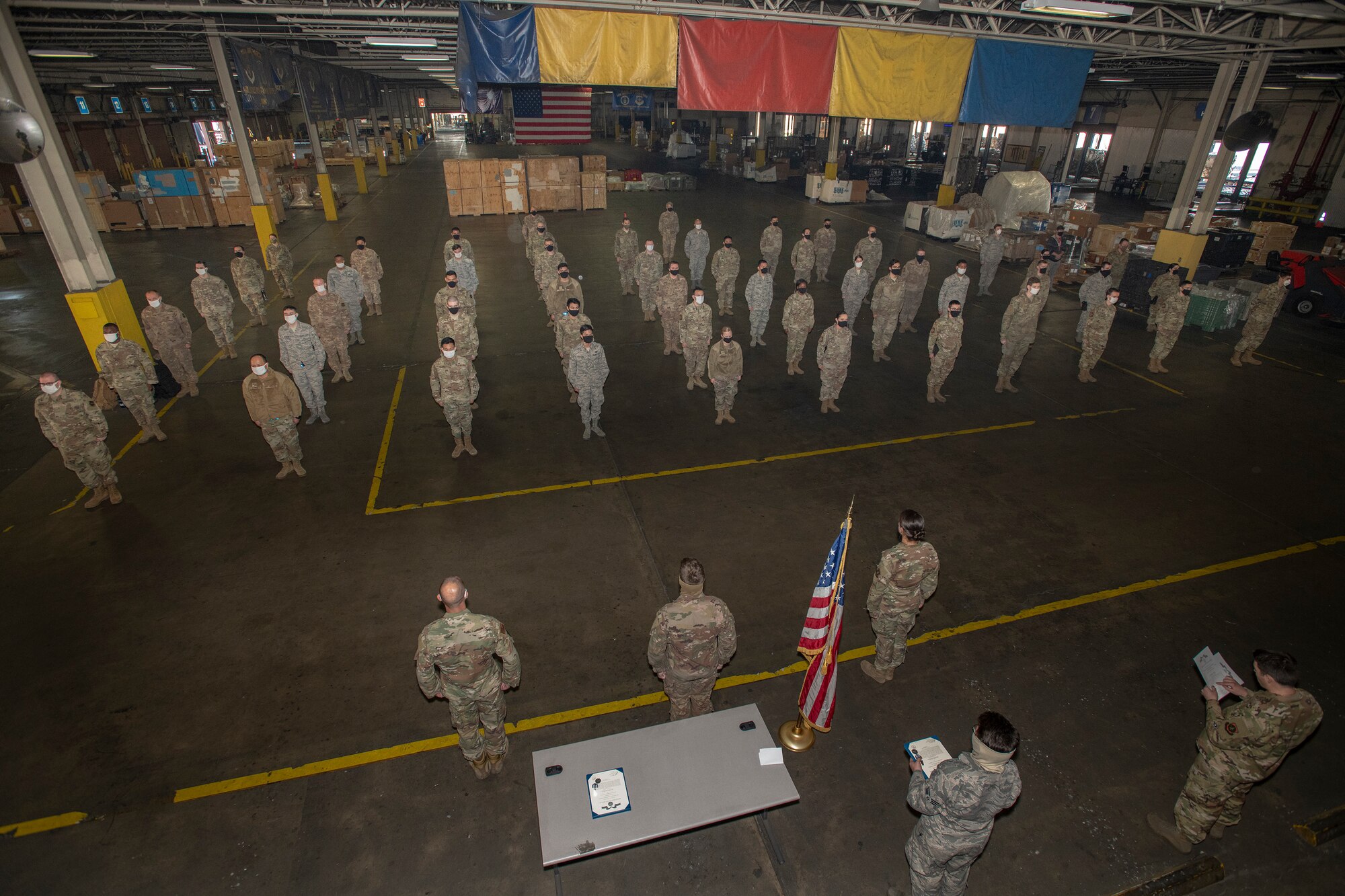 U.S. Airmen assigned to the 60th Aerial Port Squadron, stand in formation during an early morning roll call June 4, 2020, at Travis Air Force Base, California. The 60th APS continue to coordinate and deliver goods and services while enforcing the physical distancing and hygiene safety measures in place to help mitigate the spread of COVID-19. (U.S. Air Force photo by Heide Couch)