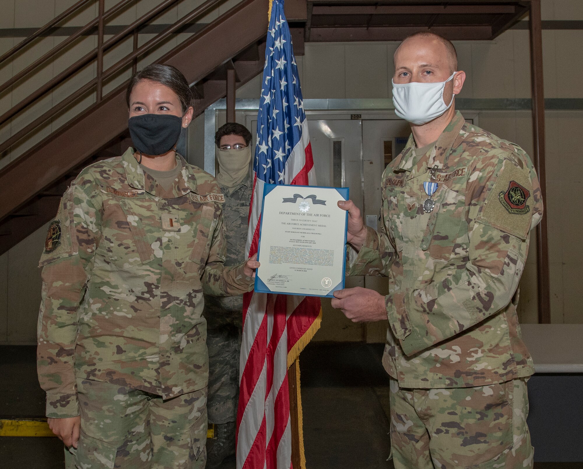 U.S. Air Force 2nd Lt. Sharon Dominguez, left, 60th Aerial Port Squadron air freight flight commander, presents the Air Force Achievement Medal to Staff Sgt. Nicholas Chaloupka, right, 60th APS ramp services shift supervisor, June 4, 2020, at Travis Air Force Base, California. The squadron continues normal operations while enforcing the physical distancing and hygiene safety measures in place to help mitigate the spread of COVID-19. (U.S. Air Force photo by Heide Couch)