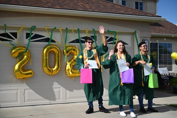 Sean Santos, left, Makayla Kearny, center, and Jackson Reams, right, wave during the “honk at a grad” parade, June 12, 2020, at Travis Air Force Base, California. The base’s Air Force Sergeants Association Chapter 1320, Airman and Family Readiness Center, and chaplain corps celebrated high school seniors unable to experience a graduation ceremony due to the COVID-19 pandemic. (U.S. Air Force photo by Airman 1st Class Karla Parra)