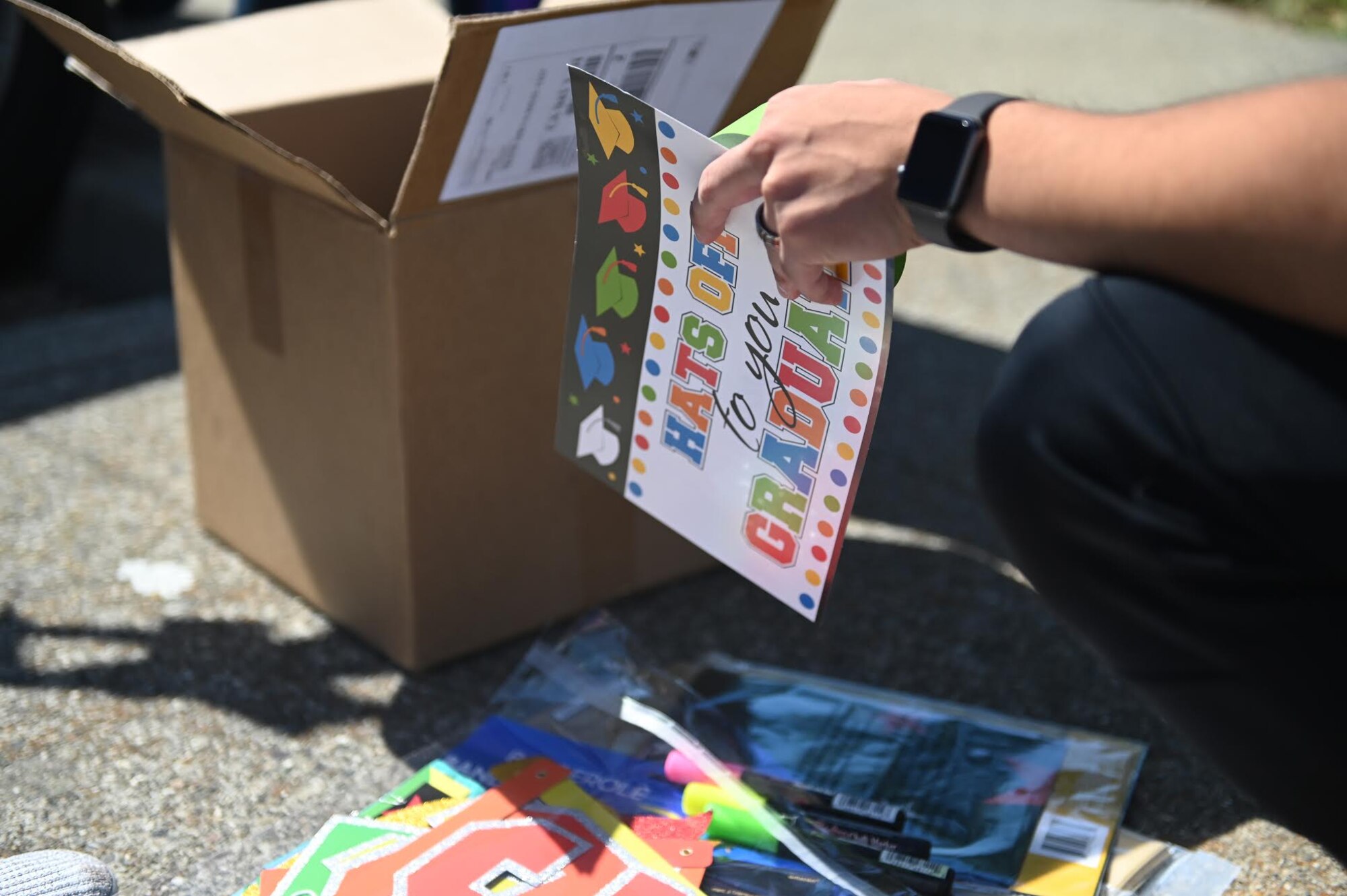 Volunteers unbox decorations to prepare for the “honk at a grad” parade, June 12, 2020, at Travis Air Force Base, California. The parade celebrated high school seniors unable to experience a graduation ceremony due to the COVID-19 pandemic. The event was a collaboration between the base’s local Air Force Sergeants Association Chapter 1320, Airman and Family Readiness Center, and the Chaplain Corps. (U.S. Air Force photo by Airman 1st Class Karla Parra)