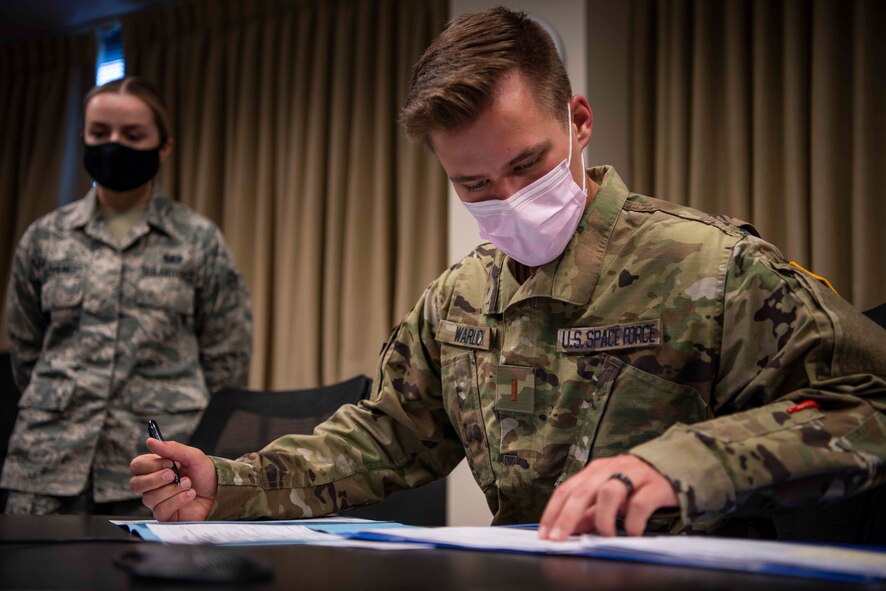 Second Lt. Zachary Warlick, 50th Space Communications Squadron senior watch officer, right, accomplishes his in-processing requirements with finance while Airman 1st Class Vlada Iakovenko, 50th Comptroller Squadron financial operations technician, left, guides him through the process at Schriever Air Force Base, Colorado, June 22, 2020. After earning his U.S. Space Force commission from the U.S. Air Force Academy, Colorado, Warlick is the first member of the USSF to be assigned to Schriever. (U.S. Air Force photo by Airman 1st Class Amanda Lovelace)
