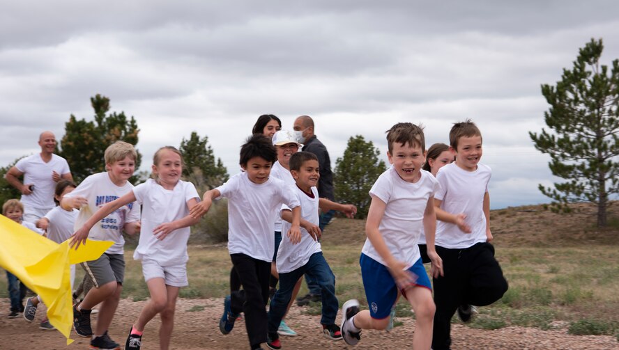Children in the School Age Care program run through a banner during the SAC color run at Schriever Air Force Base, Colorado, June 19, 2020. During the run, SAC staff members waited at different points along the route and tossed colored cornstarch at the children as they ran by. (U.S. Air Force photo by Airman 1st Class Amanda Lovelace)
