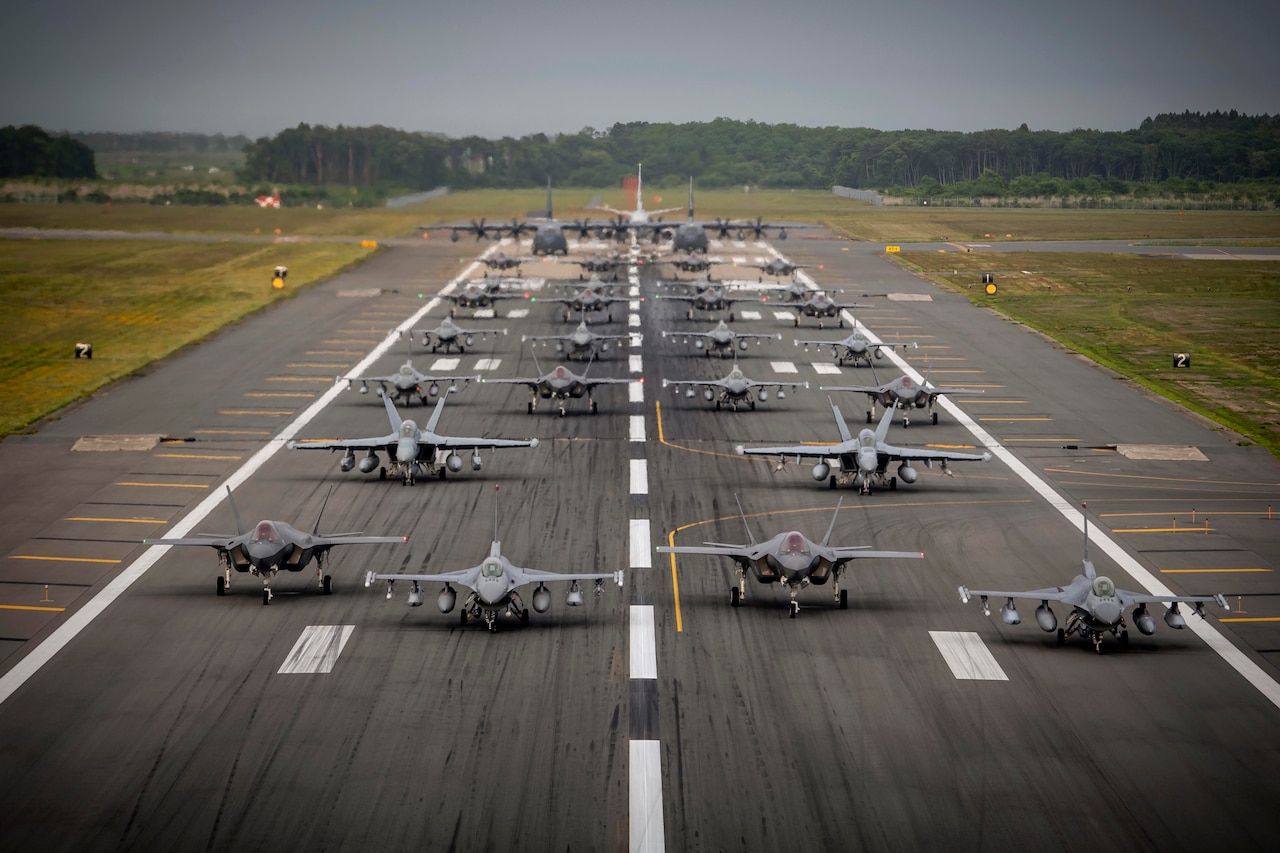 U.S. Navy, Air Force and Japanese air force aircraft sit on a runway.
