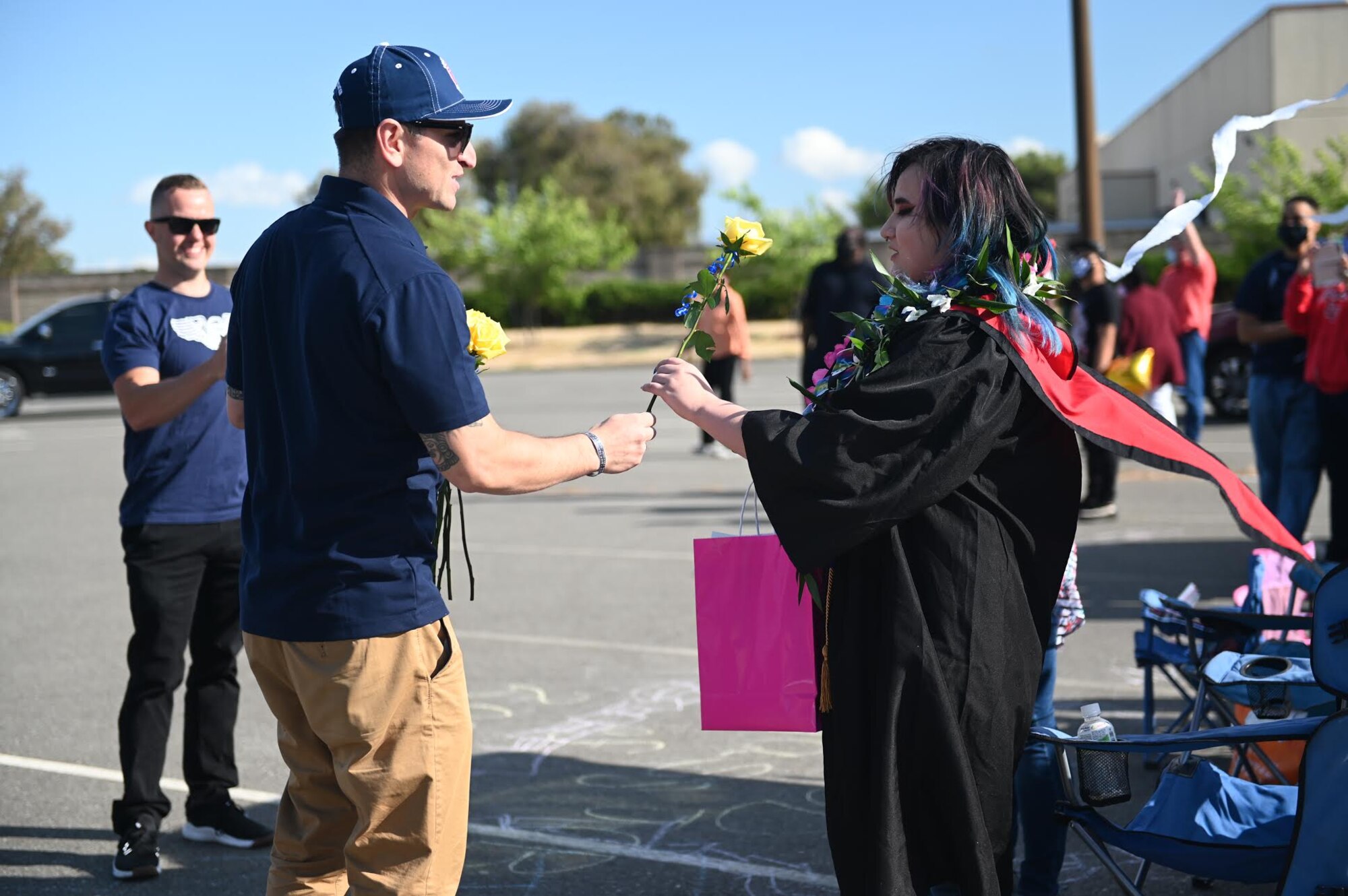 U.S Air Force Senior Master Sgt. Rey Rios, Air Force Sergeants Association Chapter 1320 senior advisor, gives Fairfield High School graduate, Keona Flower, a rose, June 12, 2020, at Travis Air Force Base, California. The base’s local AFSA Chapter 1320, Airman and Family Readiness Center, and chaplain corps collaborated for the “honk at a grad” parade to celebrate high school graduates unable to experience a graduation ceremony during the COVID-19 pandemic. (U.S. Air Force photo by Airman 1st Class Karla Parra)