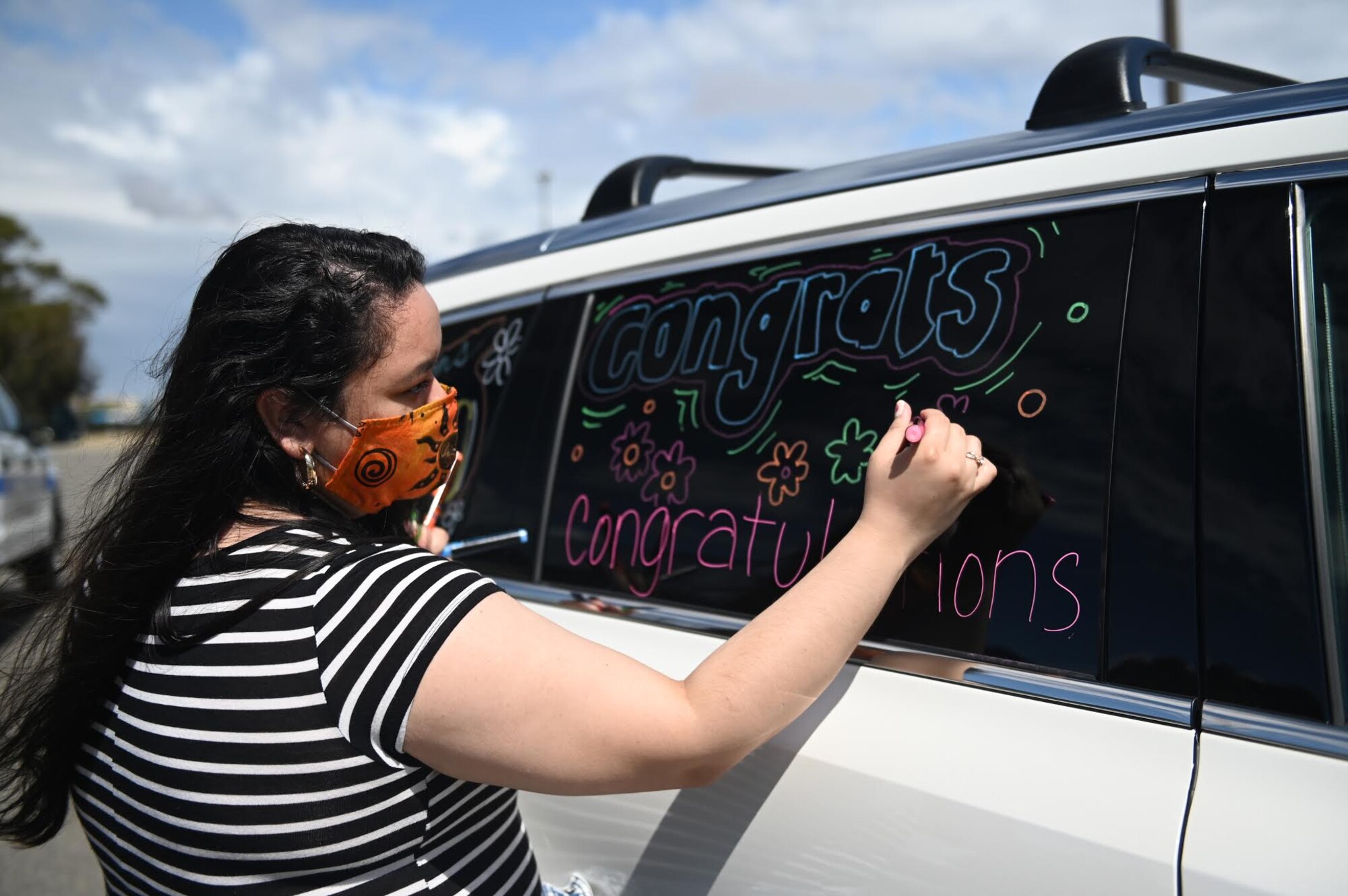 Andrea Ward, daughter of retired U.S. Air Force Master Sgt. Michael Ward, decorates a vehicle for the “honk at a grad” parade June 12, 2020, at Travis Air Force Base, California. The base’s Air Force Sergeants Association Chapter 1320, Airman and Family Readiness Center, and chaplain corps celebrated high school seniors unable to experience a graduation ceremony due to the COVID-19 pandemic. (U.S. Air Force photo by Airman 1st Class Karla Parra)