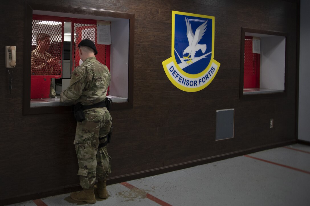 A Security Forces defender stands at the 316th Security Support Squadron armory window to receive the weapons and equipment for his shift on Joint Base Andrews, Md., June 17, 2020. The armory also houses weapons for general officers and personnel living on base.