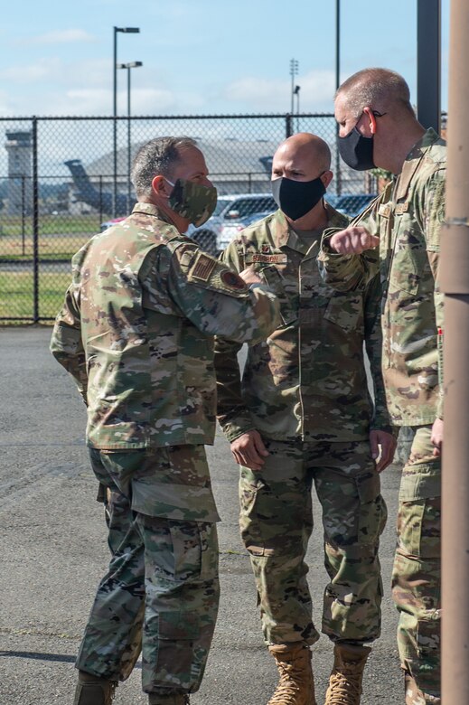 Three airmen wearing face masks stand together for a discussion.