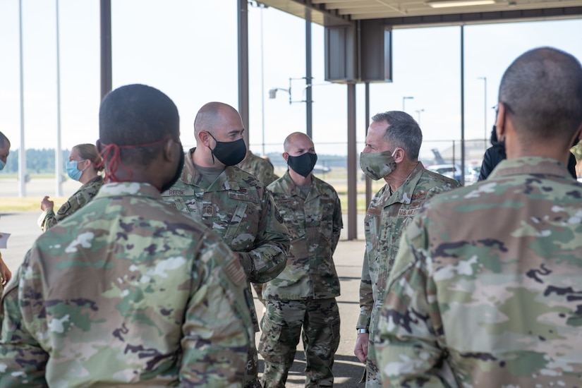 A group of airmen wearing face masks hold a discussion.