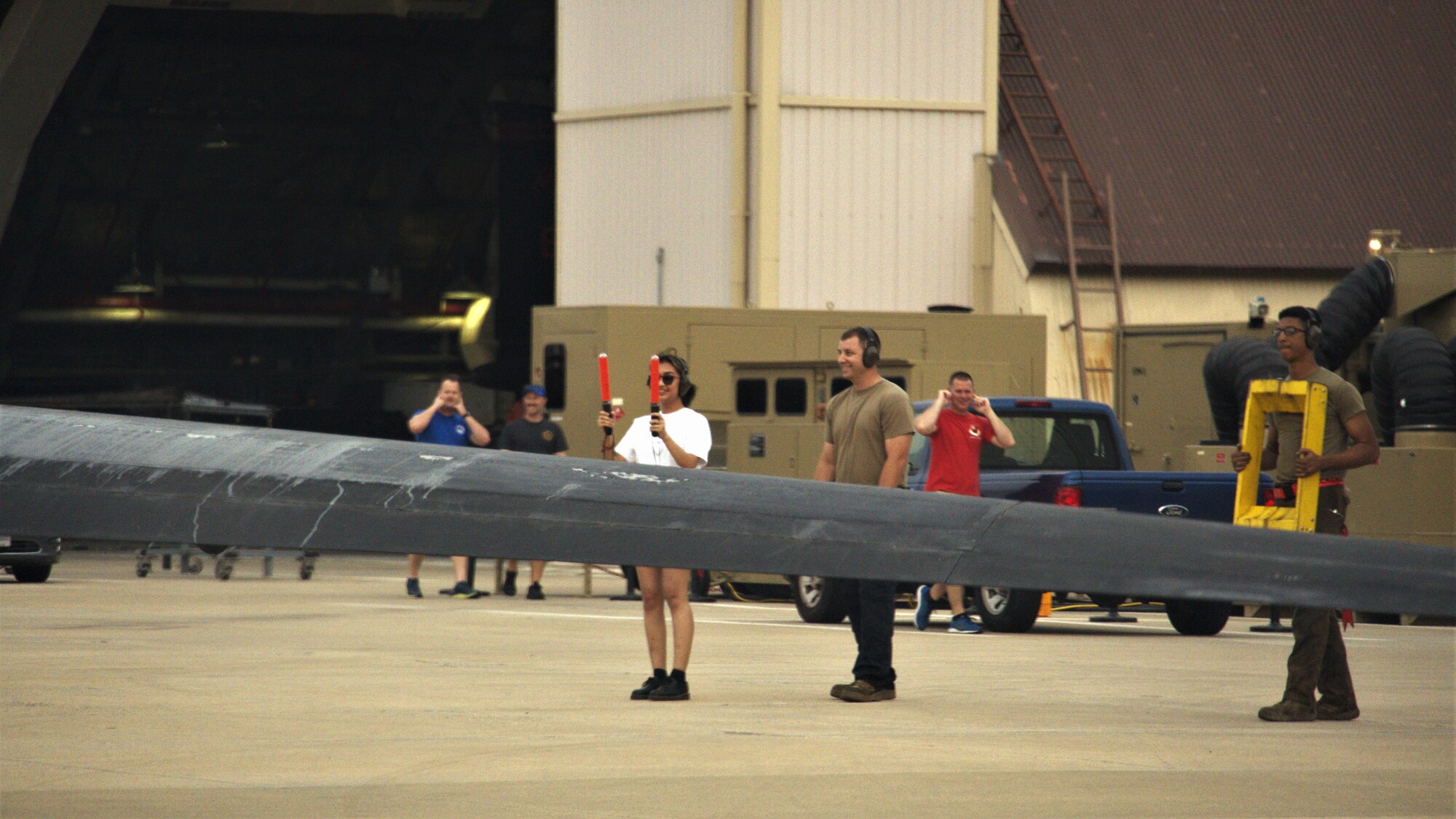 Lt. Col. Georgescu's daughter stands in front of the U-2 aircraft guiding it in with orange flashlight guides, waving in the taxiing aircraft.